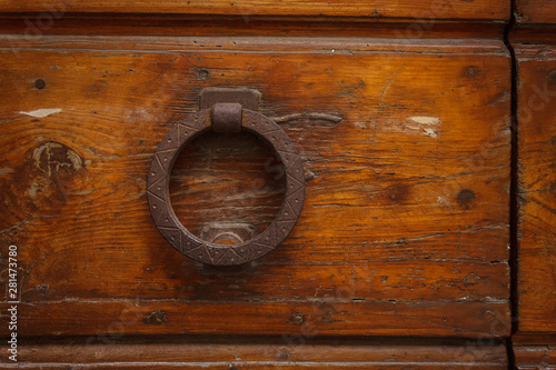 Metal old ring-shaped door handle on wooden door