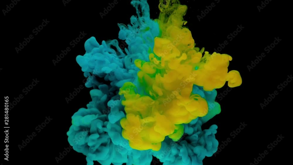 Colorful blue and yellow ink drops from above mixing in water, swirling softly underwater on black background. Timelapse. Slow motion.