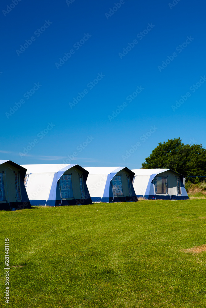 A row of identical tents at a camp site in the summer
