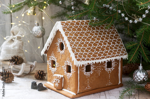 Gingerbread house and Christmas trees on a luminous background. Bokeh effect.