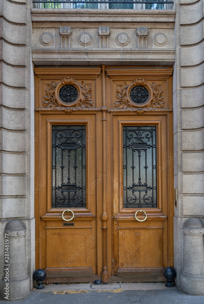 Aged wood double door entrance of old house in Paris France. Vintage wooden doorway and stone fretwork wall. Antique wood panels with ornate gratings of door windows. Aged wood double door entrance of old house in Paris France. Vintage wooden doorway and stone fretwork wall. Antique wood panels with ornate gratings of door windows.