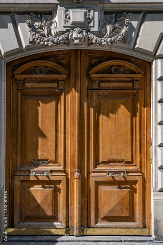 Door of an old house. Antique double door entrance of old building in Paris France. Vintage wooden door panel and stone fretwork relievo details above doorway. Carving wood framed closed door.