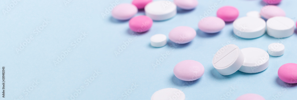 Pink and white tablets on blue background Heap of assorted various medicine tablets Horizontal banner Health care Close-up Copy space Pink and white tablets on blue background Heap of assorted various medicine tablets Horizontal banner Health care Close-up Copy space