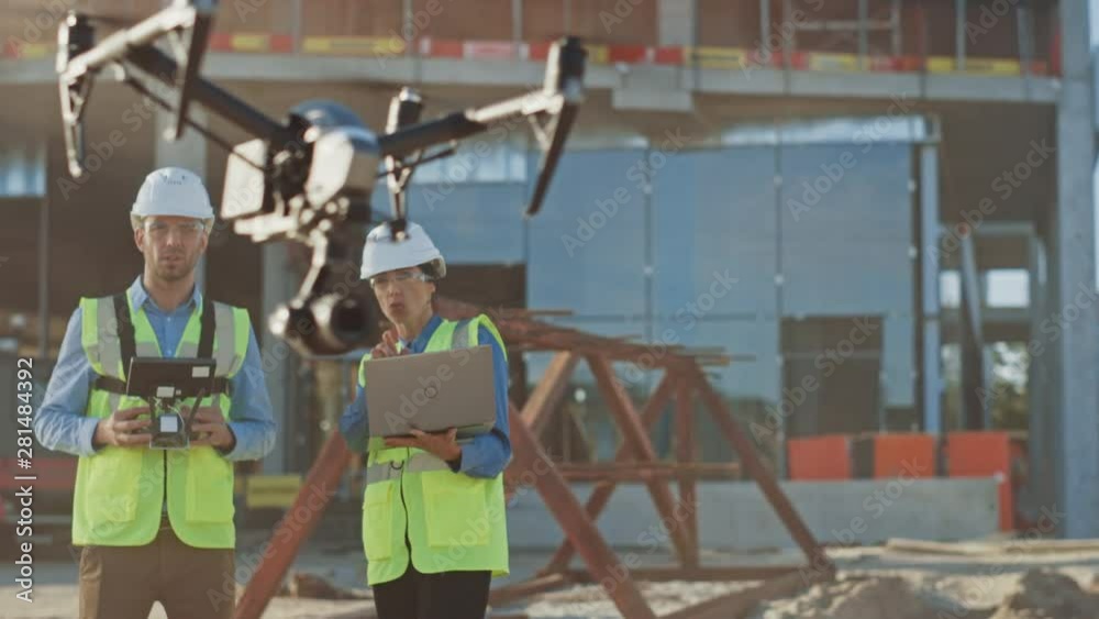 Two Specialists Use Drone on Construction Site. Architectural Engineer and Safety Engineering Inspector Fly Drone on Building Construction Site Controlling Quality. Focus on Drone