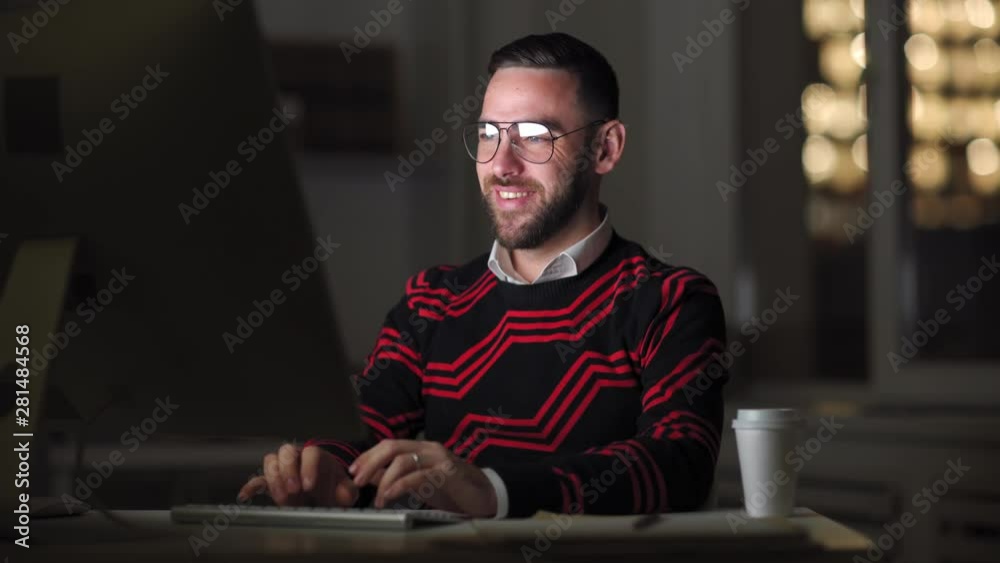 Lockdown of Caucasian man in eyeglasses sitting at working table at PC and typing messages on keyboard with different emotions on his face Lockdown of Caucasian man in eyeglasses sitting at working table at PC and typing messages on keyboard with different emotions on his face