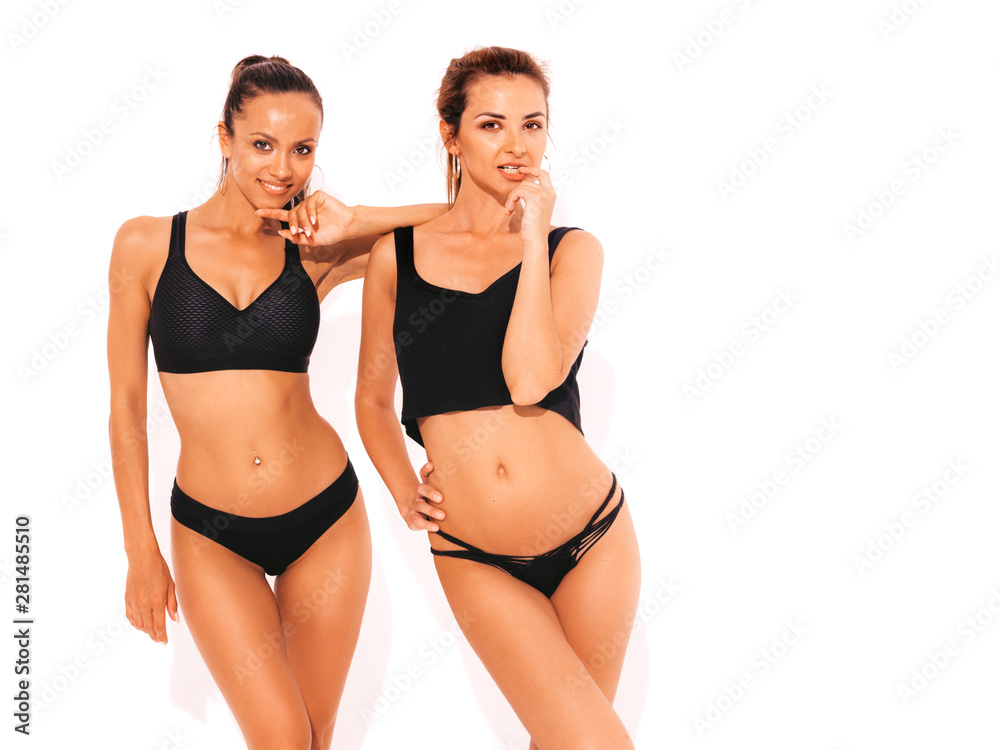 Two beautiful sexy smiling hipster women in black lingerie. Trendy hot models having fun in studio. Girls isolated on white Two beautiful sexy smiling hipster women in black lingerie. Trendy hot models having fun in studio. Girls isolated on white