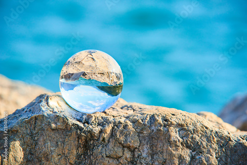 Lake Garda  Lago di Garda or Lago Benaco  seen through a glass crystal  ball placed on rock. Selective focus