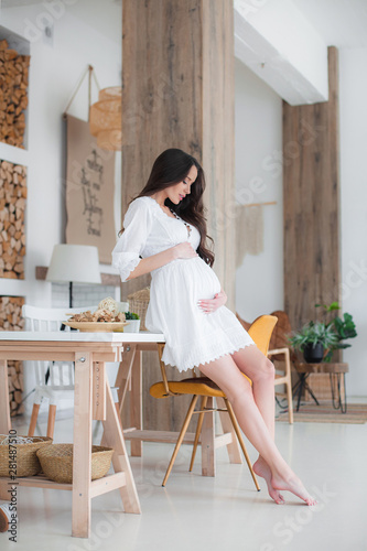 Young beautiful pregnant woman in white dress