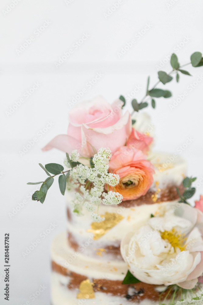 Top of Naked Wedding Cake Decorated with Gold Foil and Flowers, Three Tiered Cake, White Background, Copy Space Top of Naked Wedding Cake Decorated with Gold Foil and Flowers, Three Tiered Cake, White Background, Copy Space