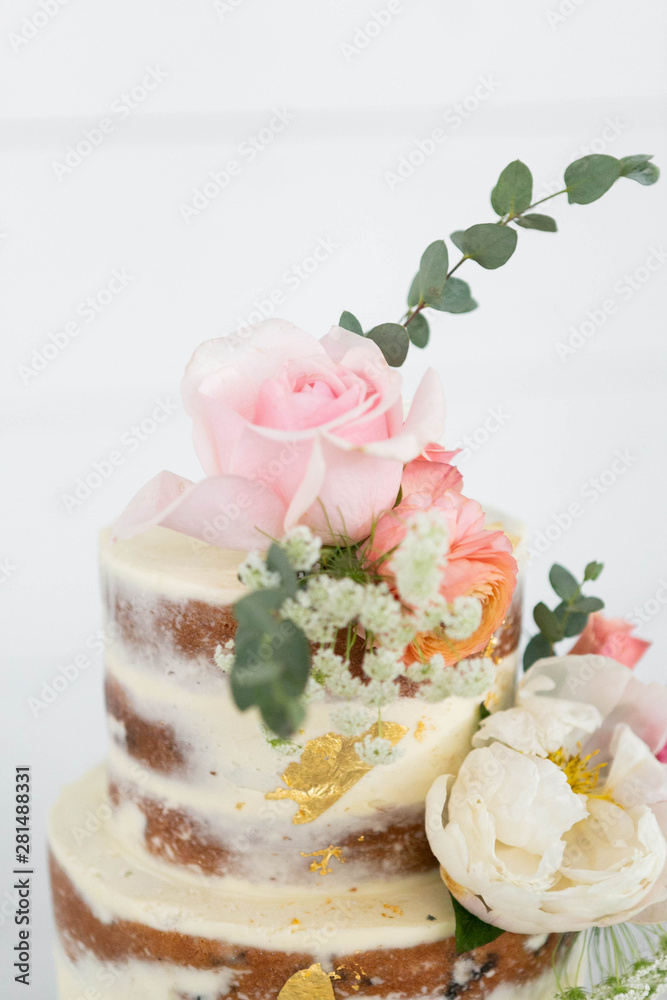 Up Close Naked Wedding Cake Decorated with Gold Foil and Flowers, Three Tiered Cake, White Background, Copy Space Up Close Naked Wedding Cake Decorated with Gold Foil and Flowers, Three Tiered Cake, White Background, Copy Space