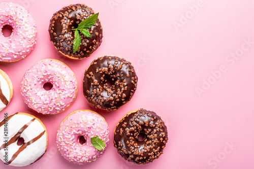 Colorful donuts on pink background with mint. Birthday party food concept with copy space. Top view