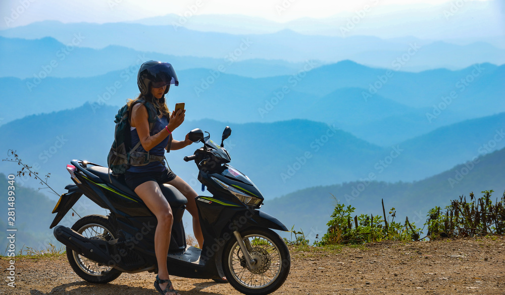 Obraz premium Girl Checks directions on her phone Tourist in Thailand on a Motorcycle