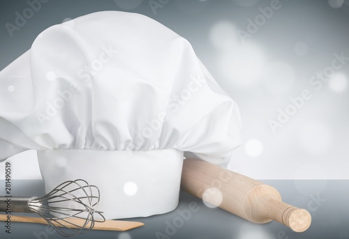 Chef hat and kitchen utensils on white background