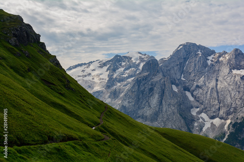 Sentiero dolomitico su un lato di monte scosceso con la Marmolada sullo sfondo