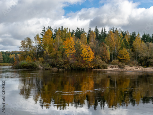 colorful autumn trees at a small forest river with beautiful reflections