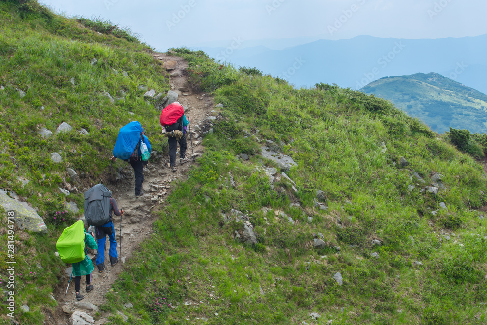 A group of hikers climb the trail to the top of the mountain. Mountain tourism.