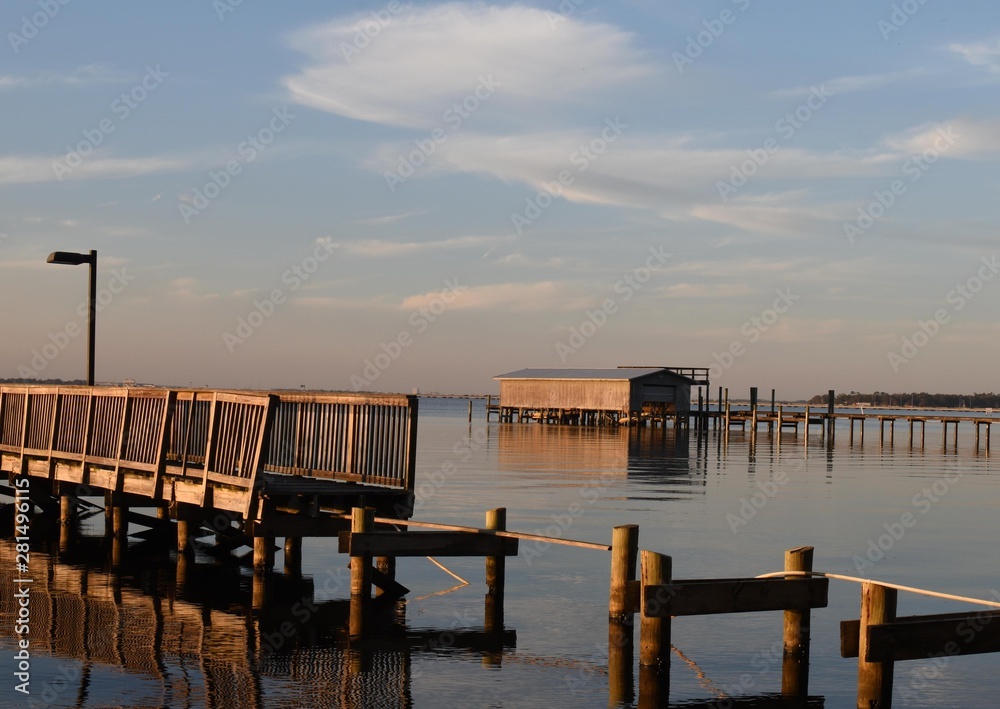 A storm damaged pier and boathouse on a river at sunset A storm damaged pier and boathouse on a river at sunset