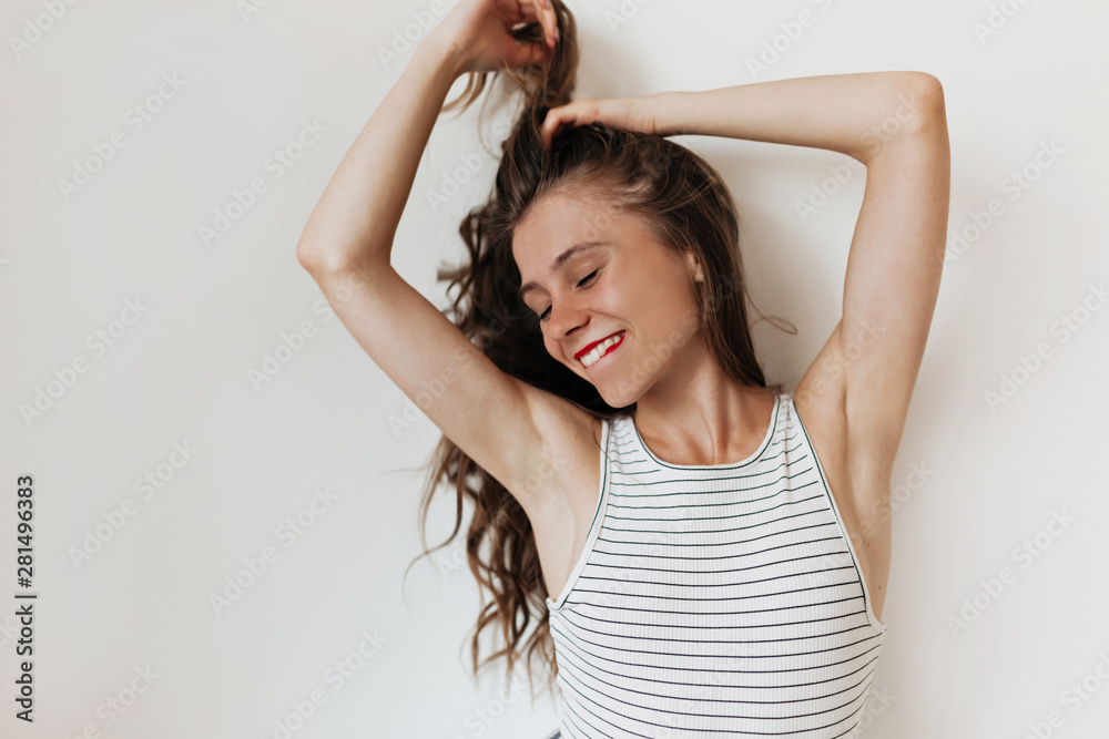 Studio portrait of attractive pretty woman with long wavy hair wearing stripped t-shirt bitting a lip and touching hair Studio portrait of attractive pretty woman with long wavy hair wearing stripped t-shirt bitting a lip and touching hair
