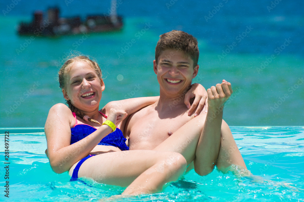 Caucasian teenagers playing in infinity swimming pool in luxury hotel, Punta Cana, Dominican Republic. Summer vacation concept
