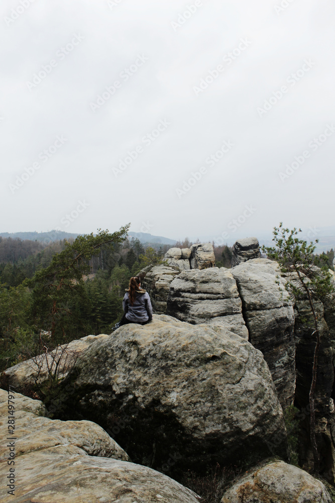 Young hiker girl on top of the rocks views into the distance.