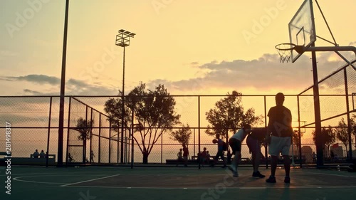 Sunset Basketball Game captures a group of young men playing basketball at sunset, creating a silhouette look.                                                                                          