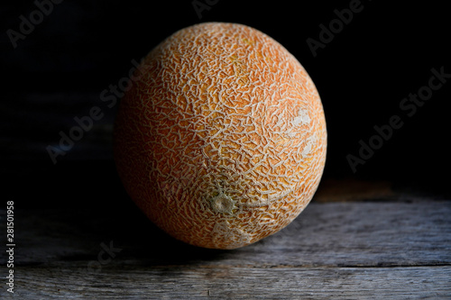 Whole fruit of a melon with a knife on an old rustic table.