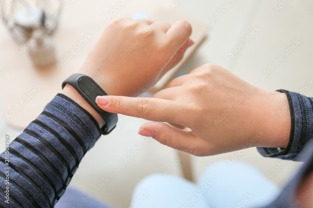 Woman checking with fitness band checking her pulse at home, closeup