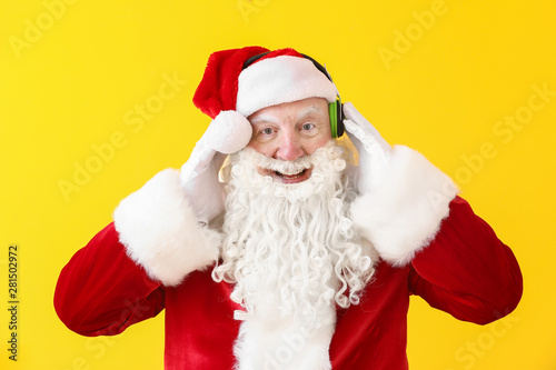 Portrait of Santa Claus listening to music on color background