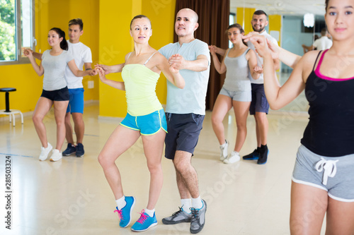 sporty girls and men learning salsa steps