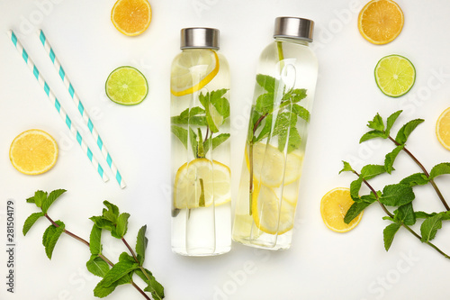 Bottles of fresh infused water and ingredients on white background