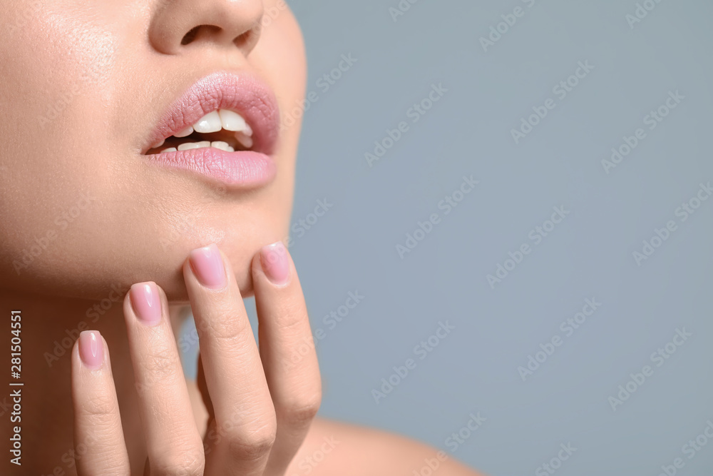 Young woman with beautiful lips on color background, closeup