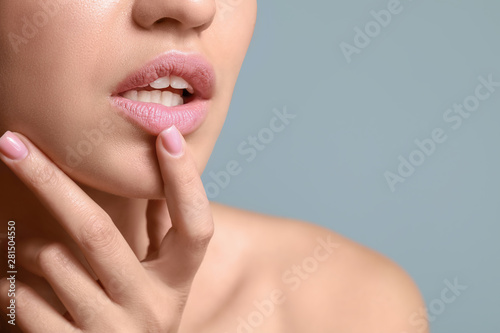 Young woman with beautiful lips on color background, closeup