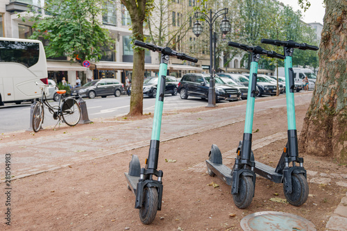 Parking E-scooters from startup company with idea of Eco friendly mobility concept of sharing Electric Scooter, park at Königsallee in Düsseldorf, Germany. Electric scooters on sidewalk in europe