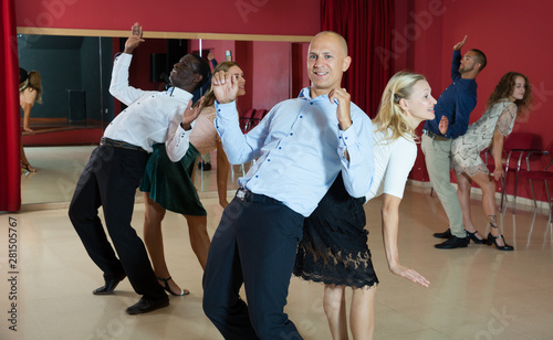 Glad smiling people practicing lindy hop technique in dance class