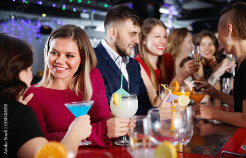Young cheerful people with cocktails having fun at nightclub