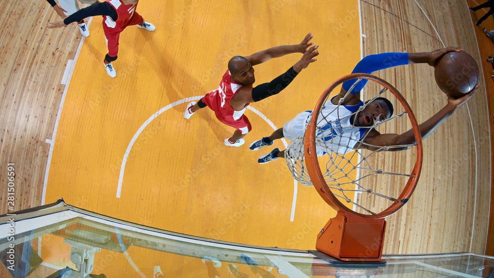 Professional basketball player in action performing slam dunk in a basketball hoop on a sports arena. View from above the hoop.