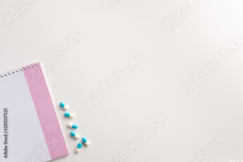 Pills and notebook on white background. Medical concept. Flat lay.