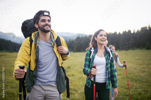 Backpackers happy young couple hiking with sticks