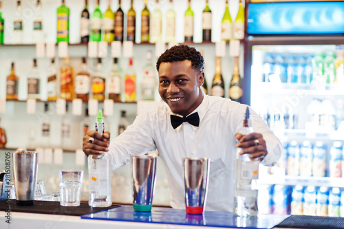 African american bartender working behind the cocktail bar. Alcoholic beverage preparation.