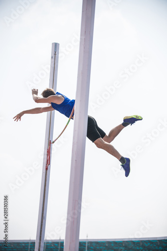 Pole vault - a young athletic man jumping over the bar