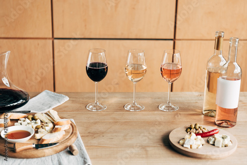 wine glasses, bottles of wine and food on wooden table