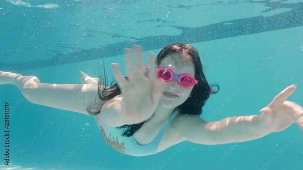 happy girl swimming underwater in pool smiling waving hand enjoying ...