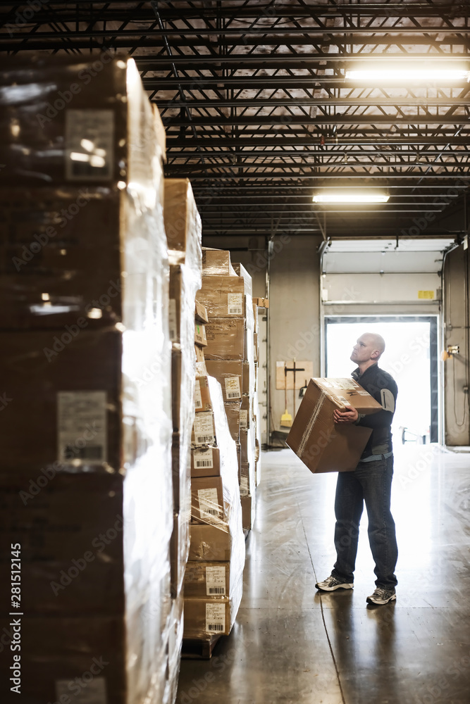 Man holding cardboard box in distribution warehouse Man holding cardboard box in distribution warehouse