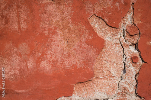 Old foundation and plaster wall with cracks. Building requiring repair closeup.