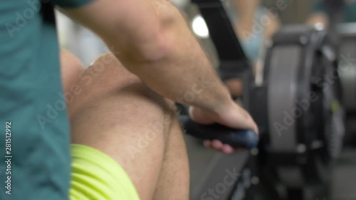 Fitness young man using rowing machine in the gym
