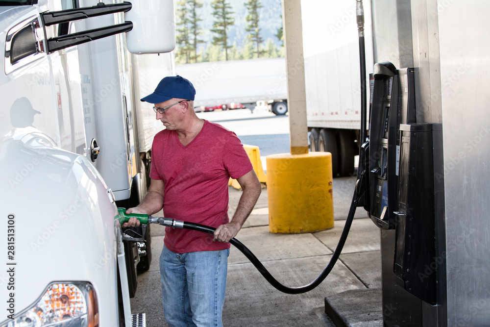 Truck driver filling truck with diesel fuel at truck stop Truck driver filling truck with diesel fuel at truck stop