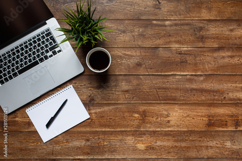 work space of a businessman. view from above . coffee black note and laptop on the desktop with black note. laptop on wooden background