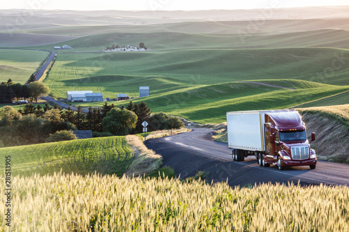 Commercial truck driving on road passing through field photo