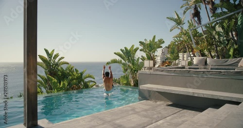 happy man running jumping in swimming pool at luxury hotel with beautiful ocean view having fun summer vacation enjoying swim at tropical resort on warm sunny day mediterranean travel 4k