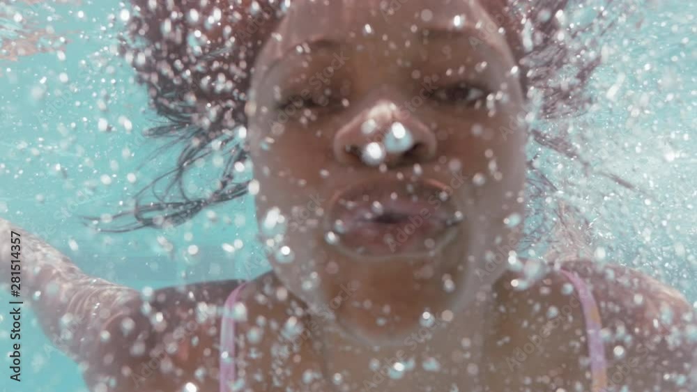 beautiful african american woman swimming underwater in pool smiling blowing kiss floating in blue crystal clear water having fun swim in summertime 4k
